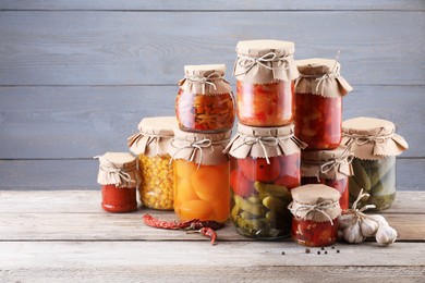Photo of Many jars with different pickled products on wooden table