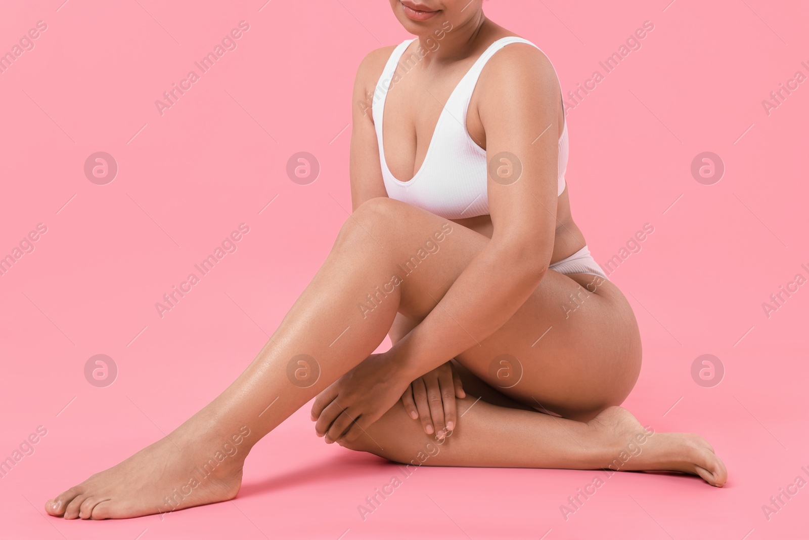 Woman in white underwear with smooth skin after epilation procedure on pink background, closeup Photo of Woman in white underwear with smooth skin after epilation procedure on pink background, closeup