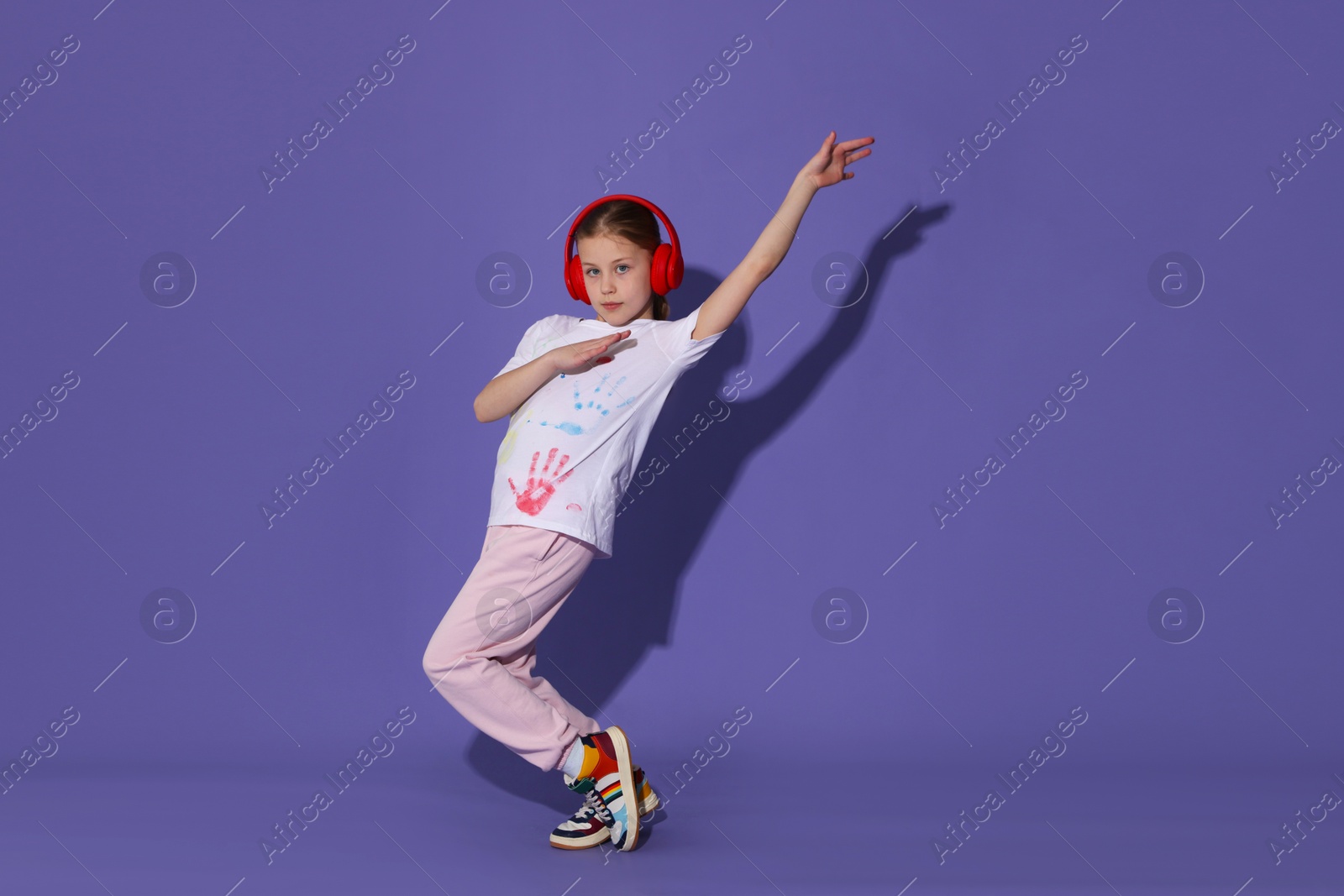 Girl with headphones dancing on purple background Photo of Girl with headphones dancing on purple background