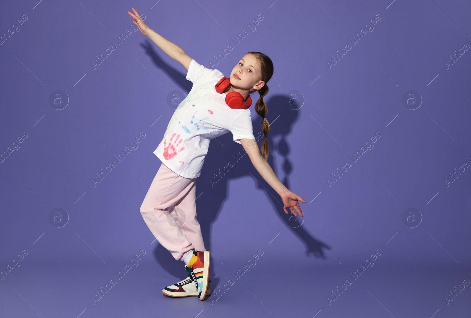 Girl with headphones dancing on purple background Photo of Girl with headphones dancing on purple background