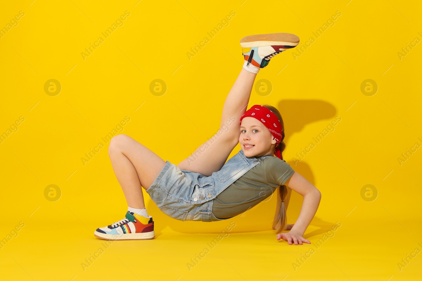 Girl in stylish clothes dancing on yellow background Photo of Girl in stylish clothes dancing on yellow background