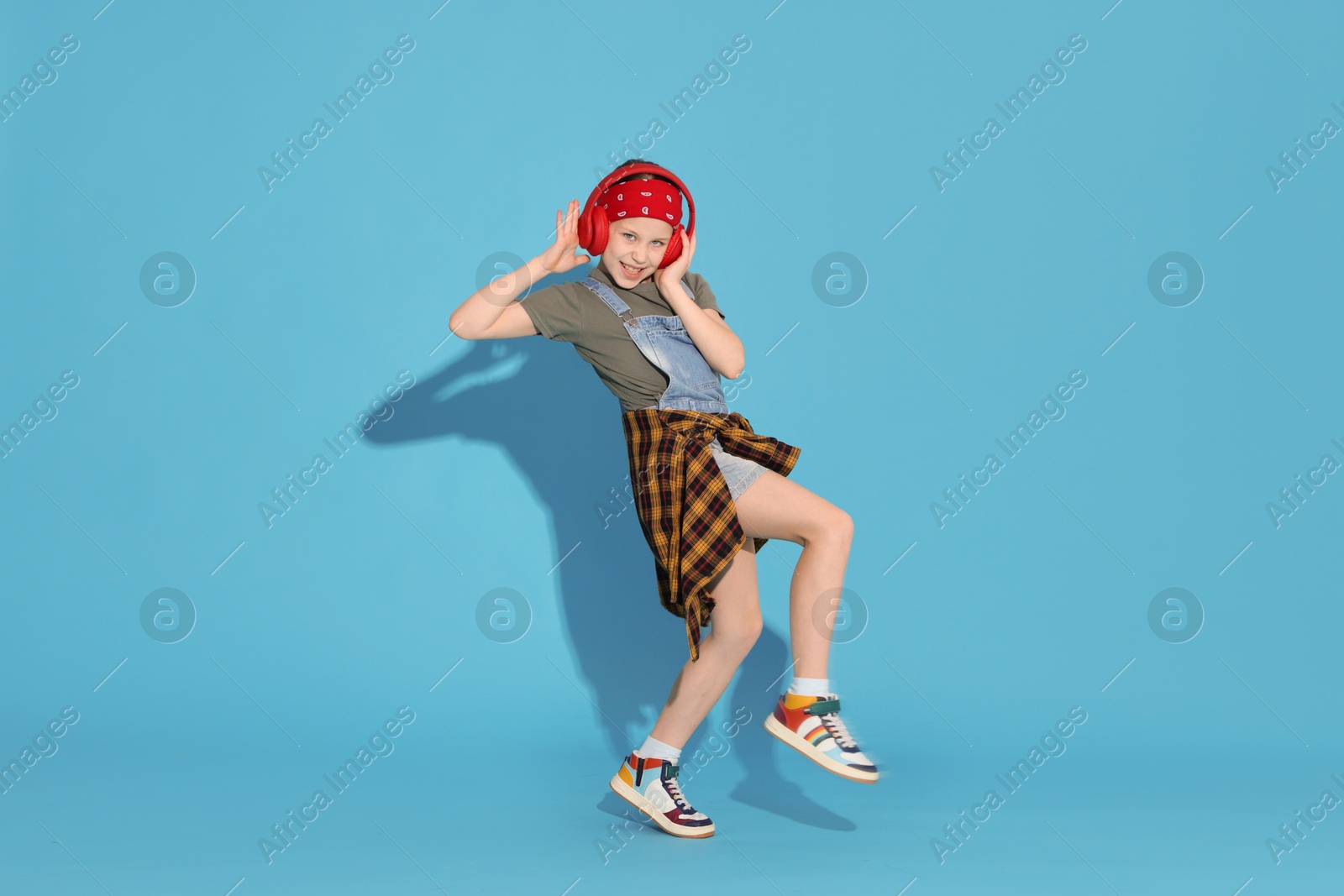 Photo of Girl with headphones dancing on light blue background
