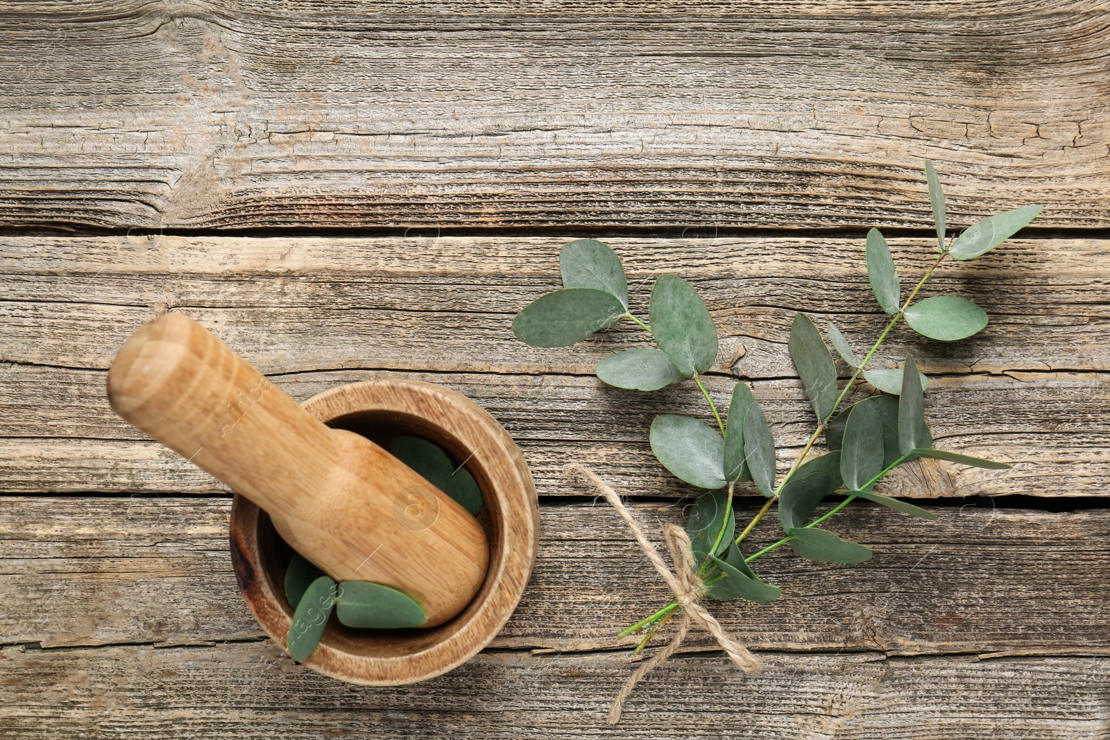 Beautiful eucalyptus branches, mortar and pestle on wooden background, top view Photo of Beautiful eucalyptus branches, mortar and pestle on wooden background, top view