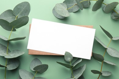 Photo of Blank card and eucalyptus branches on light green background, flat lay