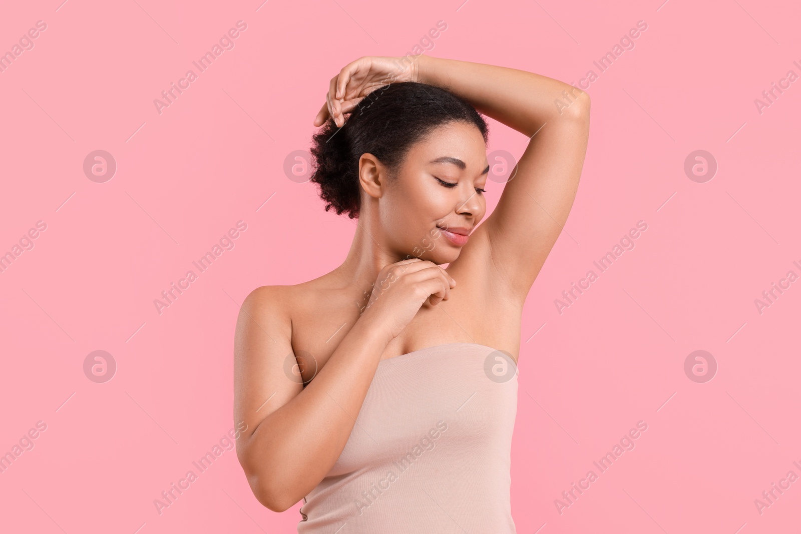 Woman showing hairless armpit after epilation procedure on pink background Photo of Woman showing hairless armpit after epilation procedure on pink background