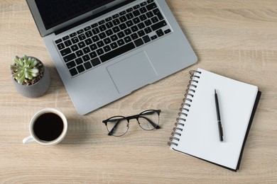 Photo of Flat lay composition with office supplies, laptop and cup of coffee on wooden table
