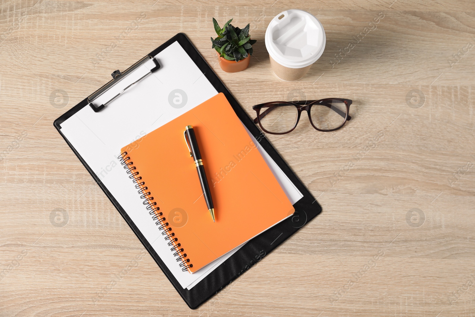 Flat lay composition with office supplies, houseplant and takeaway paper cup on wooden table Photo of Flat lay composition with office supplies, houseplant and takeaway paper cup on wooden table