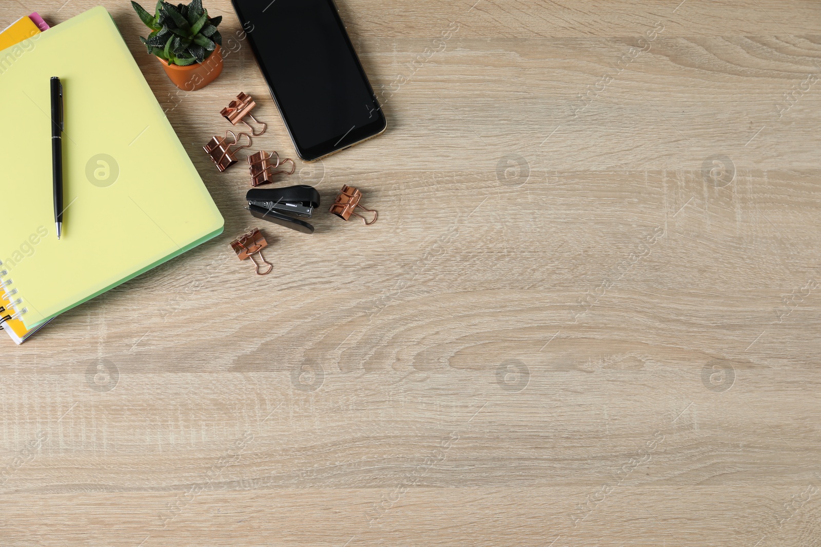 Flat lay composition with office supplies, smartphone and houseplant on wooden table. Space for text Photo of Flat lay composition with office supplies, smartphone and houseplant on wooden table. Space for text