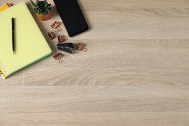 Photo of Flat lay composition with office supplies, smartphone and houseplant on wooden table. Space for text