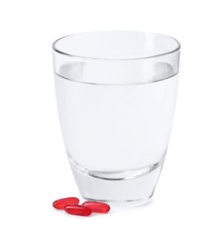 Photo of Collagen capsules and glass of water isolated on white