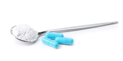 Photo of Collagen powder in spoon and pills isolated on white