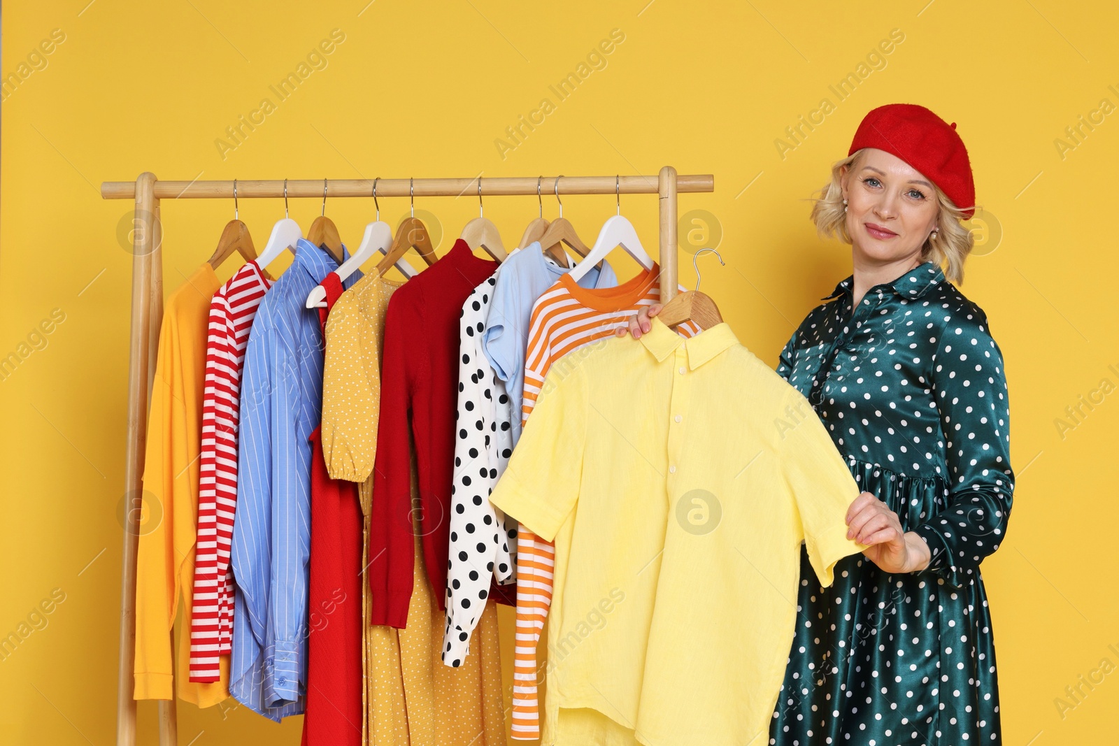 Fashion stylist and rack with clothes on yellow background Photo of Fashion stylist and rack with clothes on yellow background