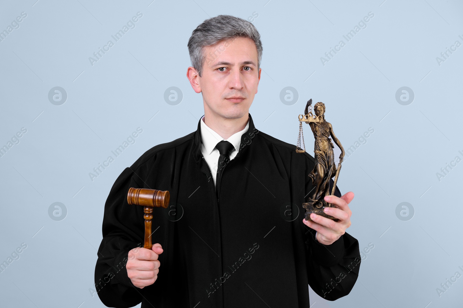 Judge with mallet and statue of Lady Justice on grey background Photo of Judge with mallet and statue of Lady Justice on grey background