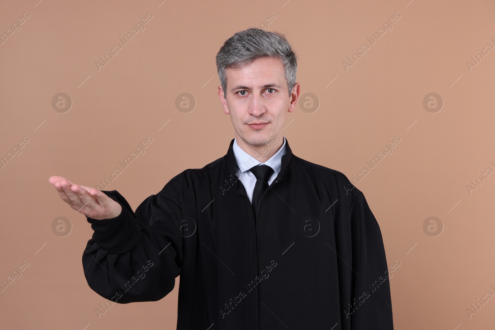 Judge in court dress holding something on beige background Photo of Judge in court dress holding something on beige background