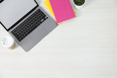 Photo of Flat lay composition with office supplies, laptop, houseplant and takeaway paper cup on light wooden table. Space for text