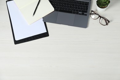 Photo of Flat lay composition with office supplies, laptop, glasses and houseplant on light wooden table. Space for text