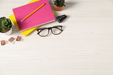 Photo of Flat lay composition with office supplies and houseplants on light wooden table. Space for text