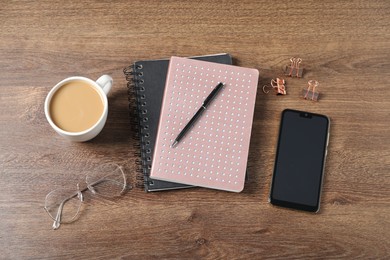 Photo of Flat lay composition with office supplies, cup of coffee and smartphone on wooden table