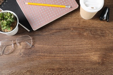 Photo of Flat lay composition with office supplies, takeaway cup of coffee and houseplant on wooden table. Space for text