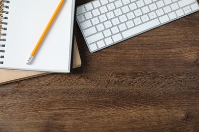 Photo of Office supplies and keyboard on wooden table, flat lay. Space for text