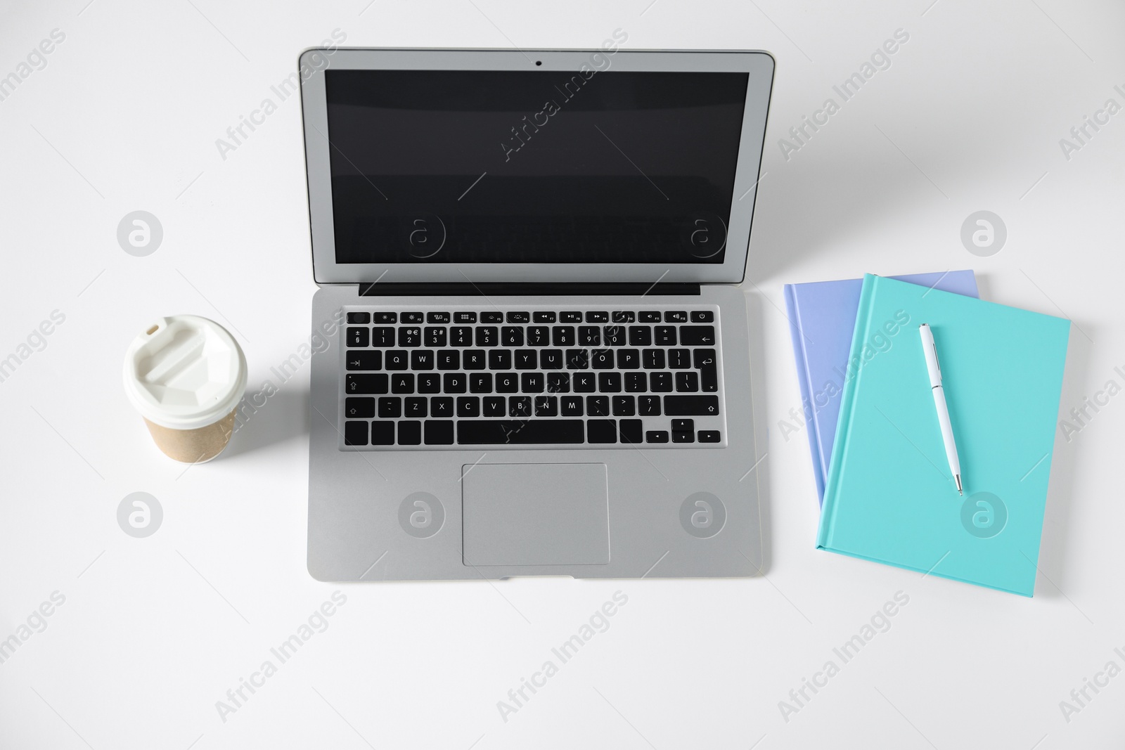 Office supplies, laptop and takeaway paper cup on white table, above view Photo of Office supplies, laptop and takeaway paper cup on white table, above view