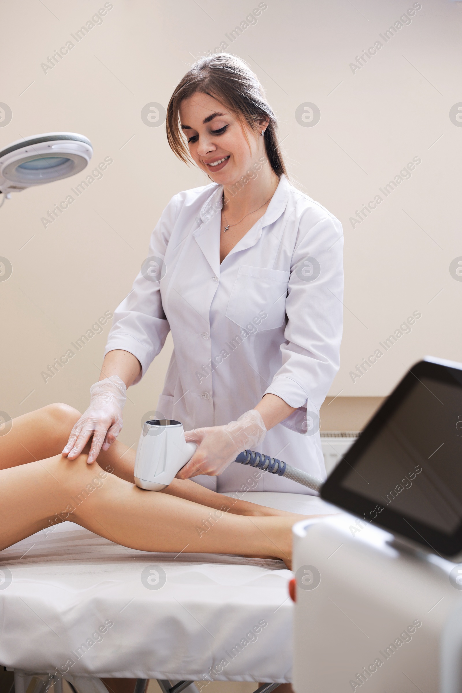 Laser hair removal procedure. Smiling cosmetologist working with client in beauty salon Photo of Laser hair removal procedure. Smiling cosmetologist working with client in beauty salon