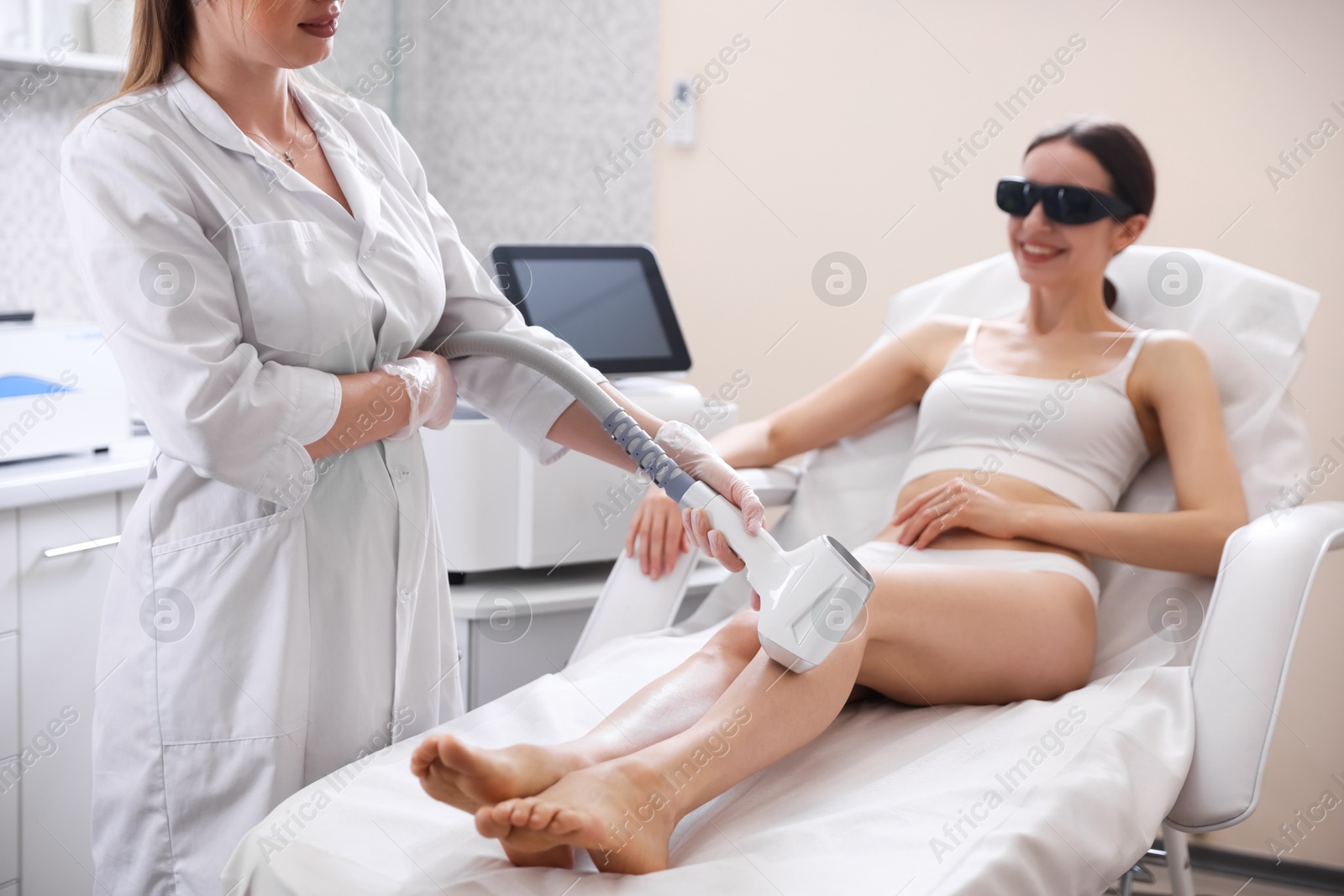 Laser hair removal procedure. Cosmetologist working with smiling client in beauty salon, closeup Photo of Laser hair removal procedure. Cosmetologist working with smiling client in beauty salon, closeup