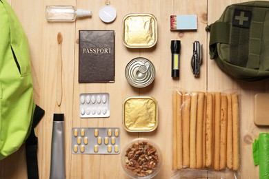 Photo of Survival kit. Different emergency supplies on wooden table, flat lay