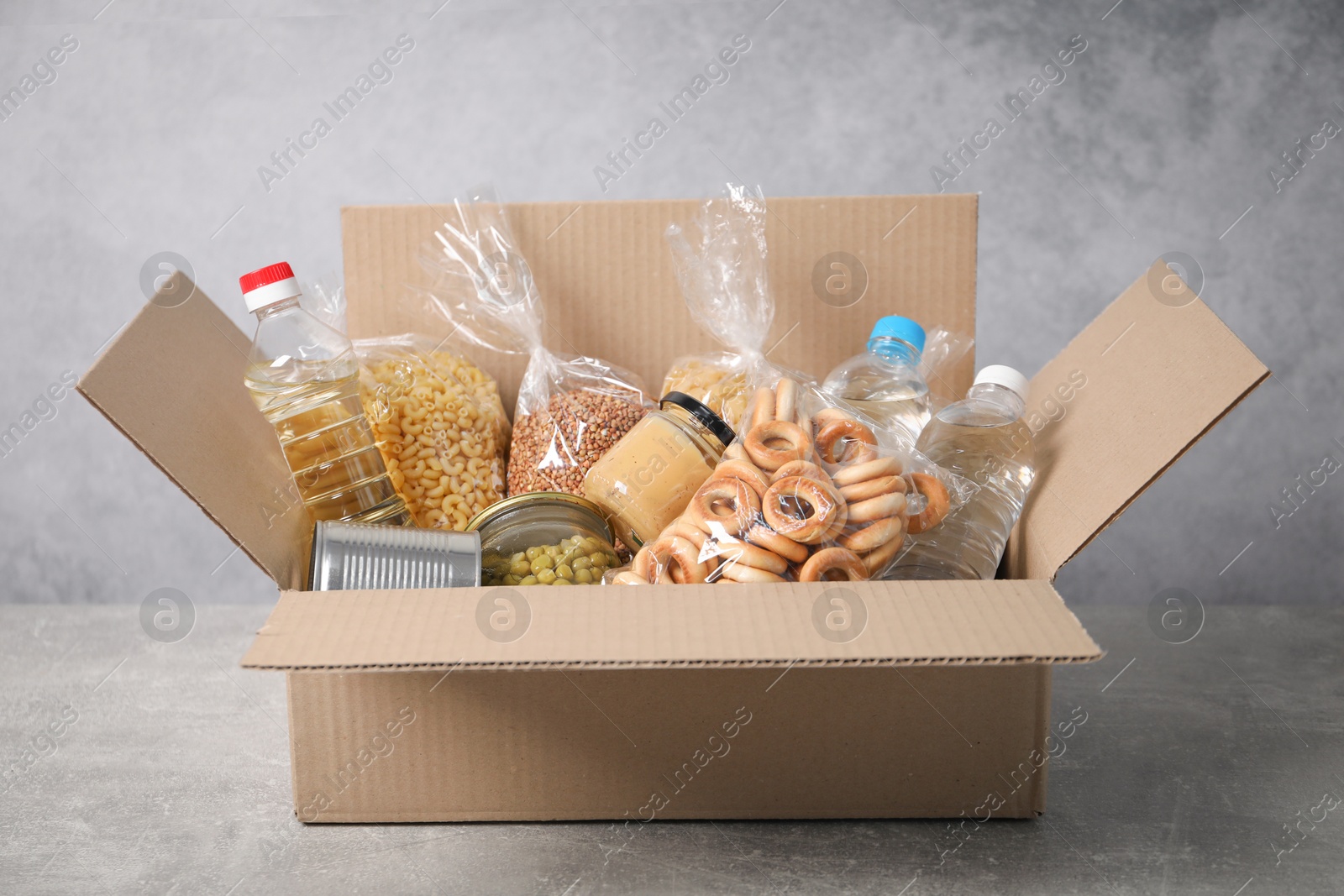Different food products in box on gray textured table Photo of Different food products in box on gray textured table