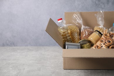 Photo of Different food products in box on gray textured table, space for text