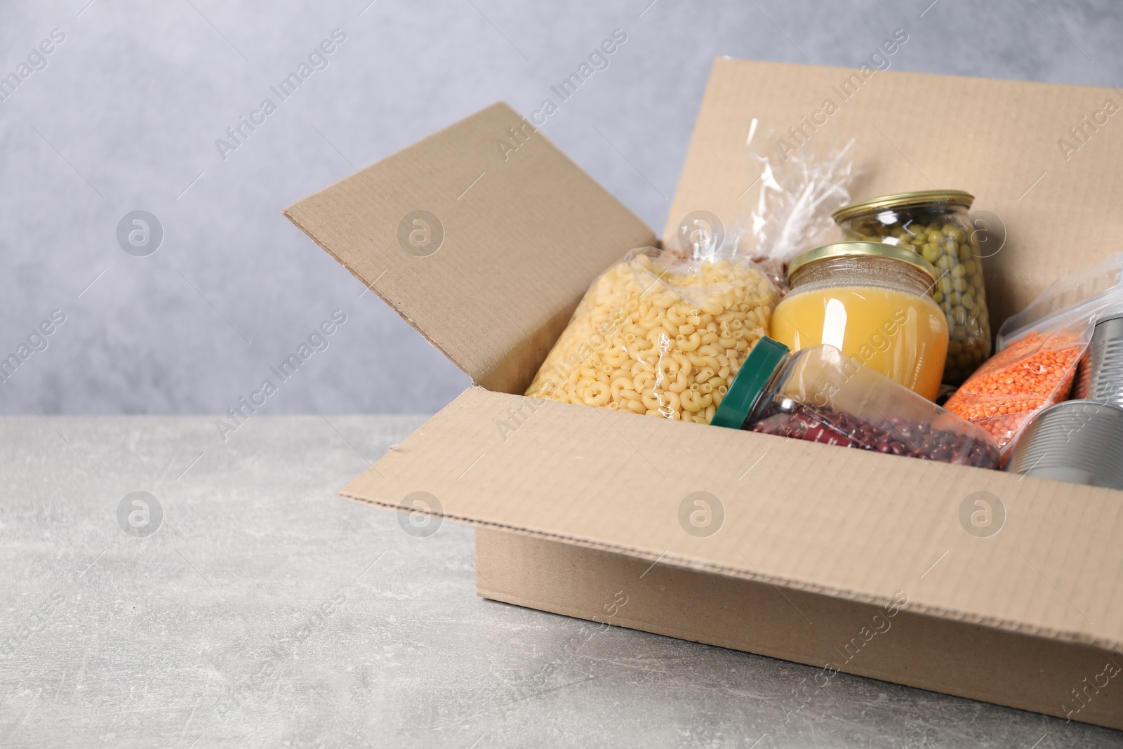 Different food products in box on gray textured table Photo of Different food products in box on gray textured table