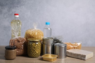 Photo of Different food products on wooden table against gray background