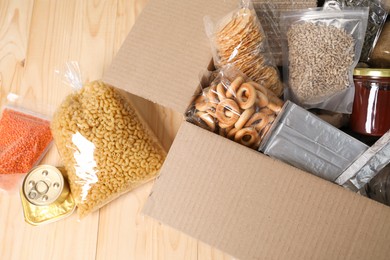 Photo of Different food products in box on wooden table, flat lay
