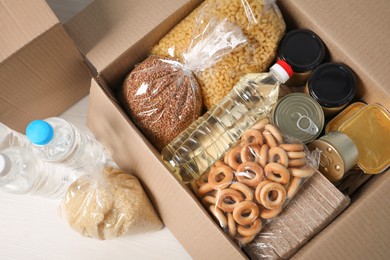 Photo of Different food products in box on light wooden table, flat lay