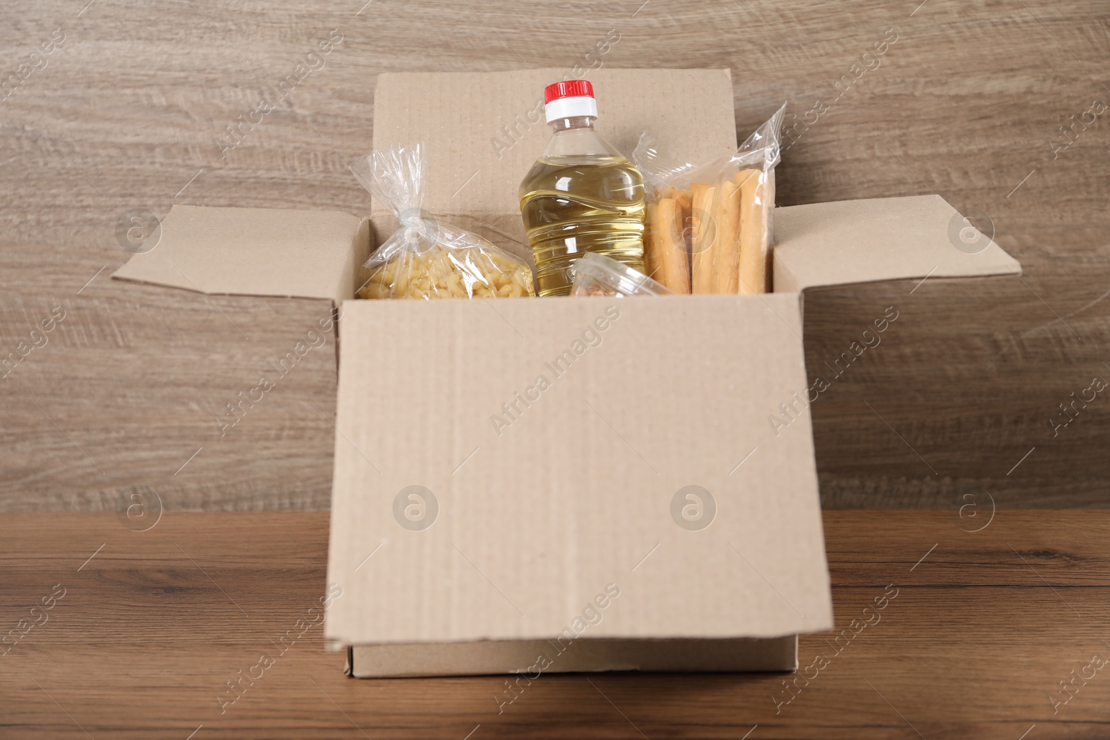 Different food products in box on wooden table Photo of Different food products in box on wooden table
