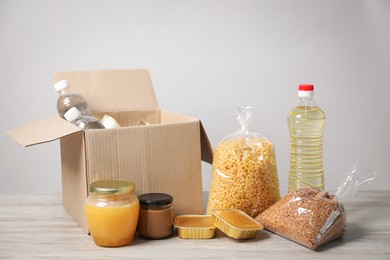 Photo of Different food products and box on wooden table against light background