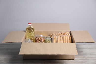 Photo of Different food products in box on wooden table against light background