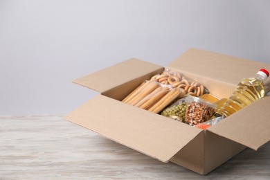 Photo of Different food products in box on wooden table against light background