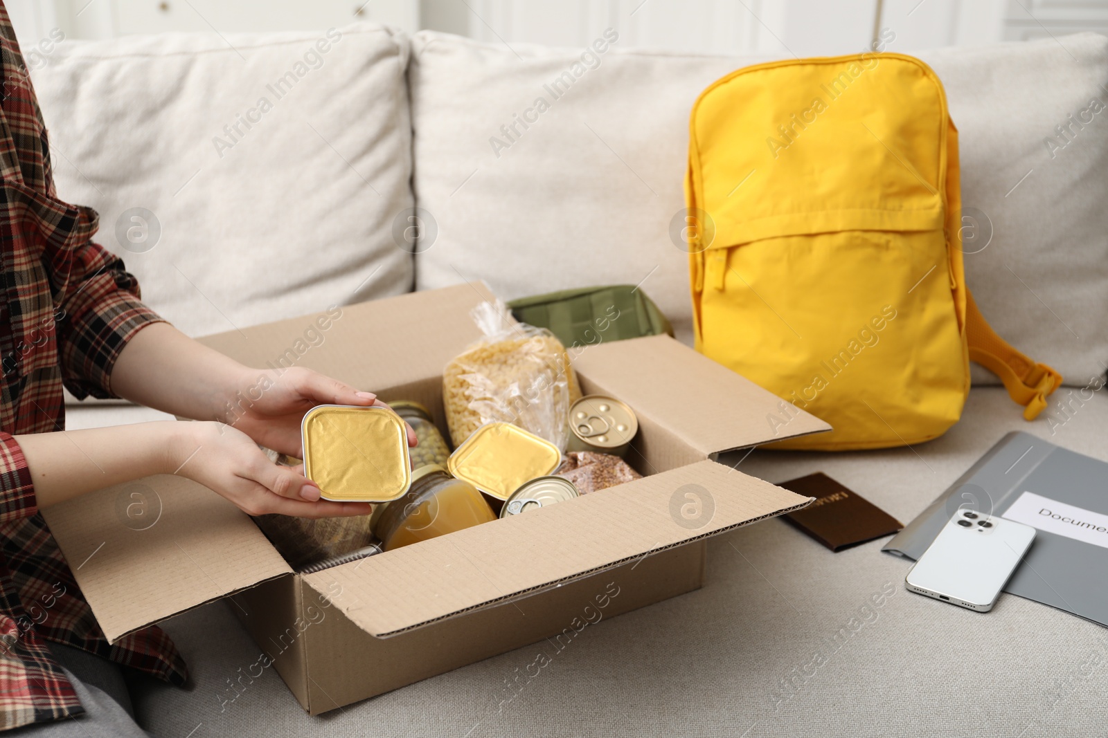 Survival kit. Woman packing different emergency supplies on sofa indoors, closeup Photo of Survival kit. Woman packing different emergency supplies on sofa indoors, closeup