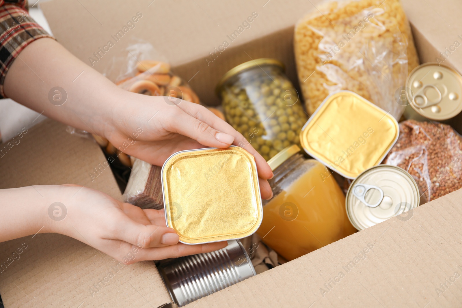 Woman putting different food products into box, top view Photo of Woman putting different food products into box, top view