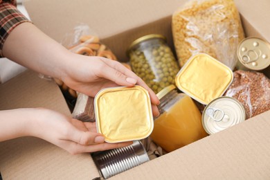 Photo of Woman putting different food products into box, top view