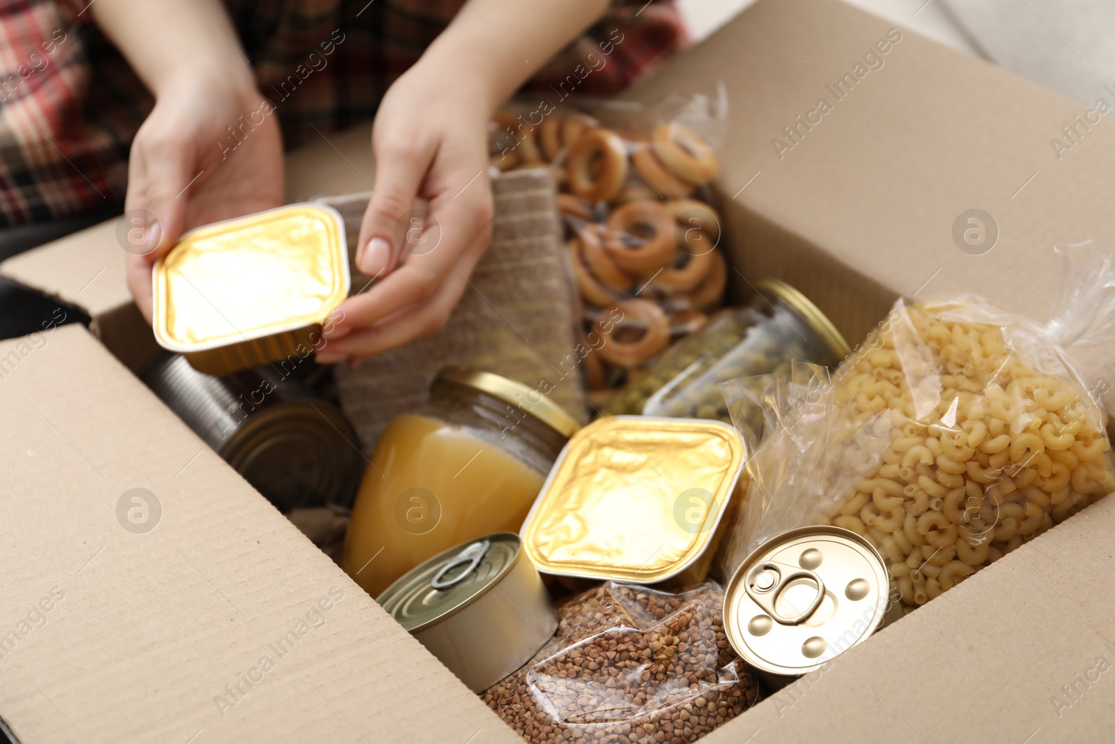 Woman putting different food products into box, closeup Photo of Woman putting different food products into box, closeup