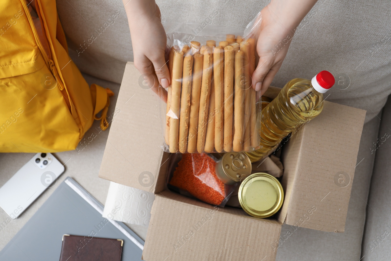 Survival kit. Woman packing different emergency supplies on sofa, top view Photo of Survival kit. Woman packing different emergency supplies on sofa, top view