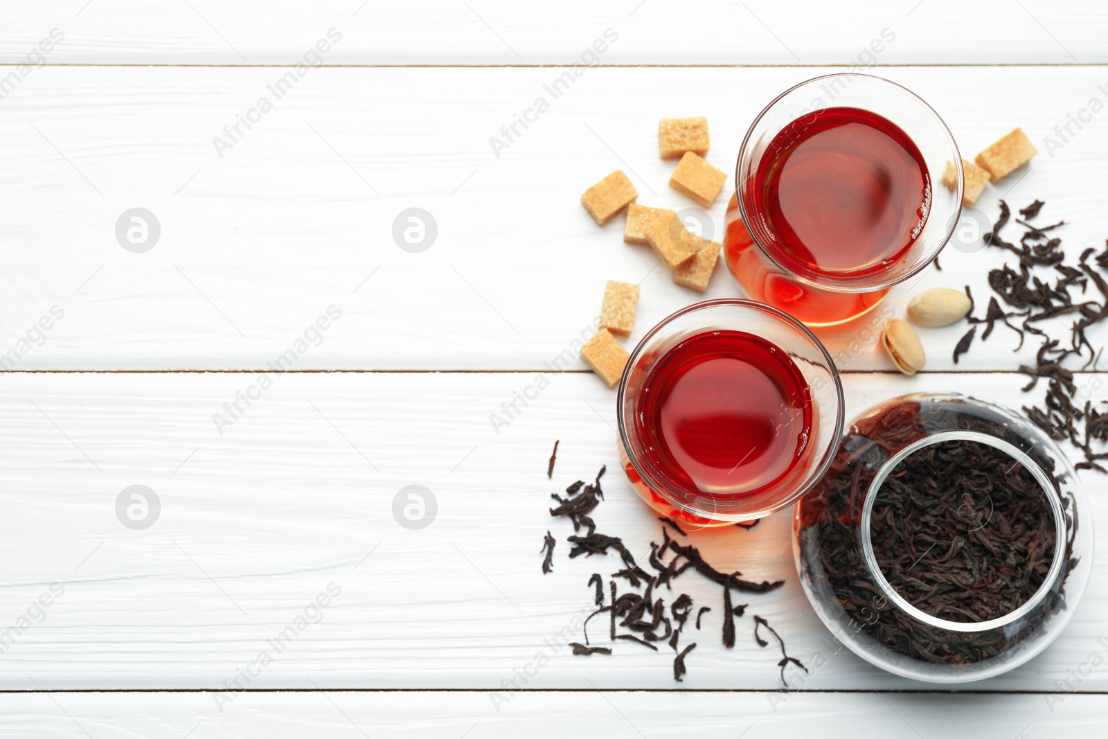 Tasty Turkish tea, sugar and pistachios on white wooden table, flat lay. Space for text Photo of Tasty Turkish tea, sugar and pistachios on white wooden table, flat lay. Space for text