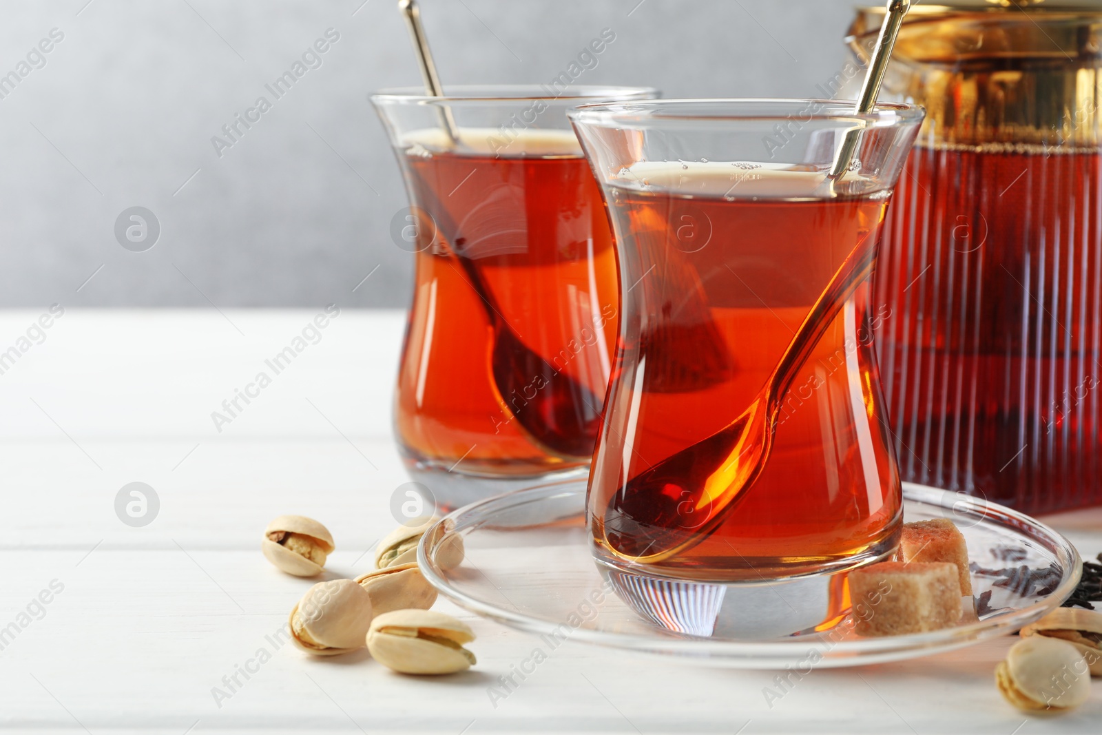 Tasty Turkish tea, sugar and pistachios on white wooden table, closeup Photo of Tasty Turkish tea, sugar and pistachios on white wooden table, closeup