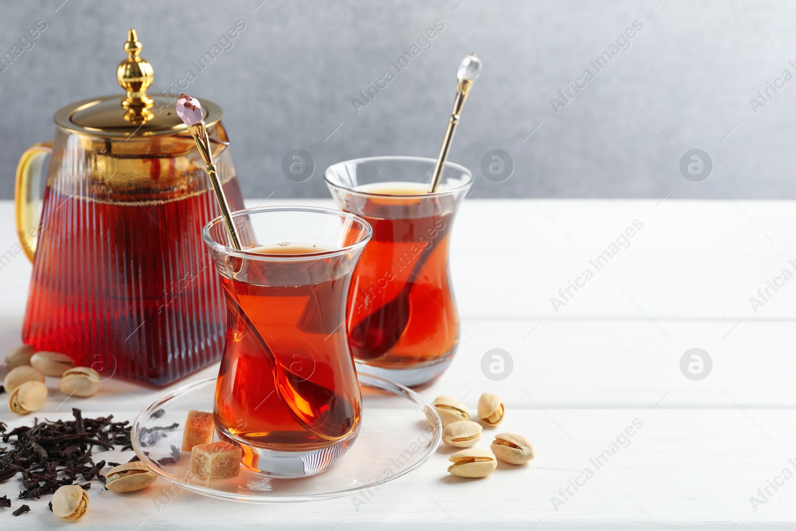 Tasty Turkish tea, sugar and pistachios on white wooden table. Space for text Photo of Tasty Turkish tea, sugar and pistachios on white wooden table. Space for text
