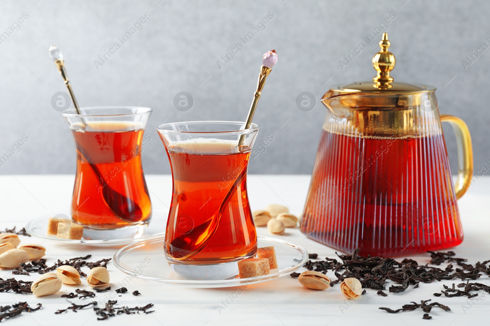Tasty Turkish tea, sugar and pistachios on white wooden table Photo of Tasty Turkish tea, sugar and pistachios on white wooden table