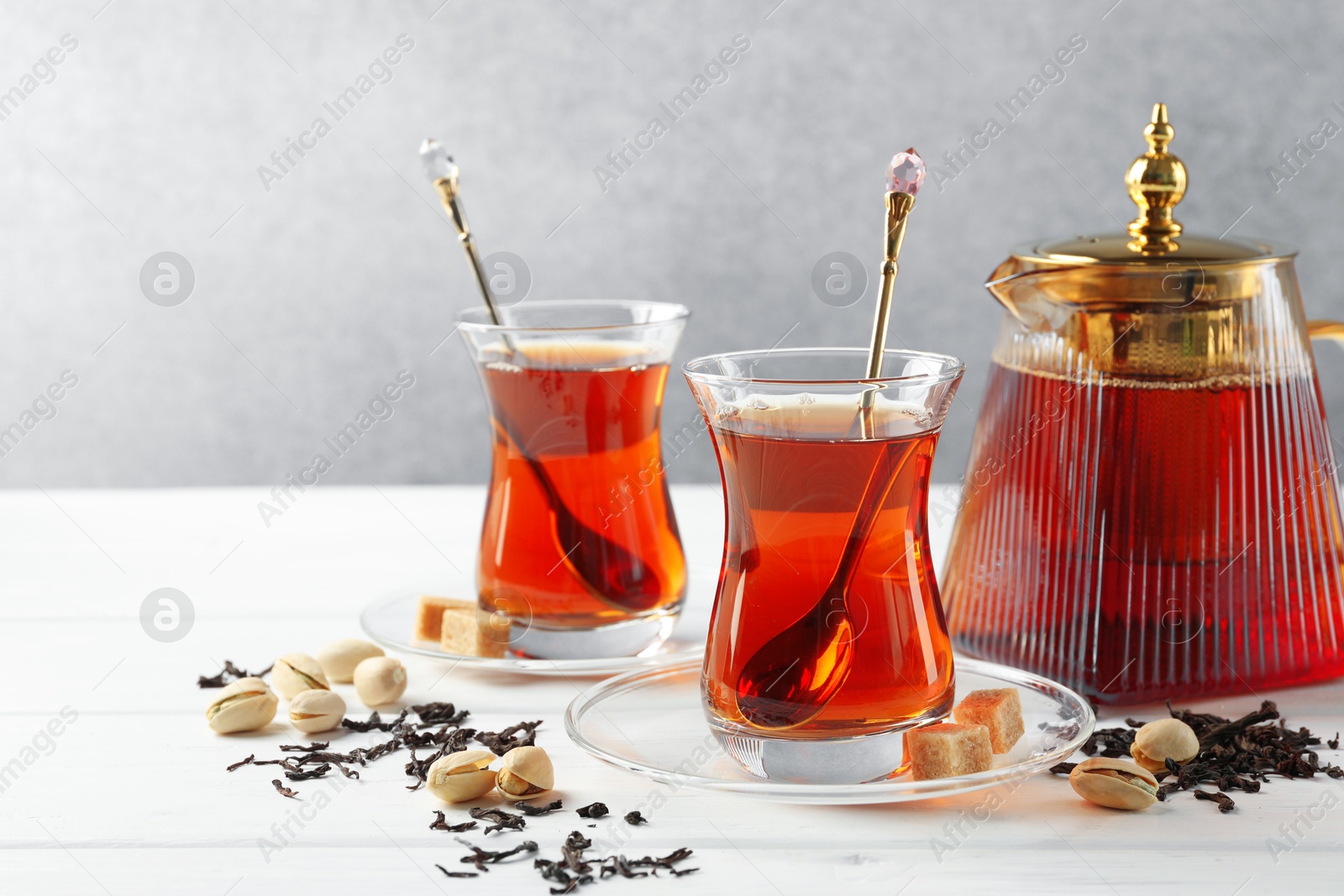 Tasty Turkish tea, sugar and pistachios on white wooden table. Space for text Photo of Tasty Turkish tea, sugar and pistachios on white wooden table. Space for text