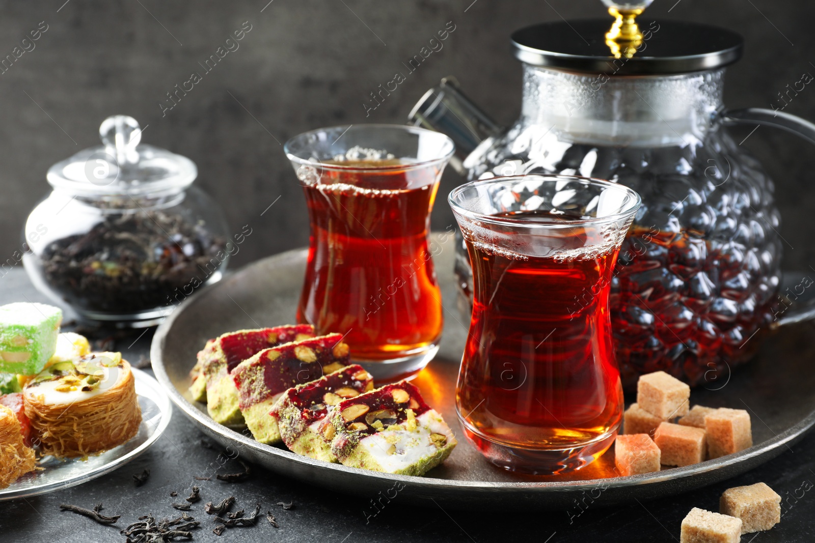 Tasty Turkish tea and delight on black table Photo of Tasty Turkish tea and delight on black table