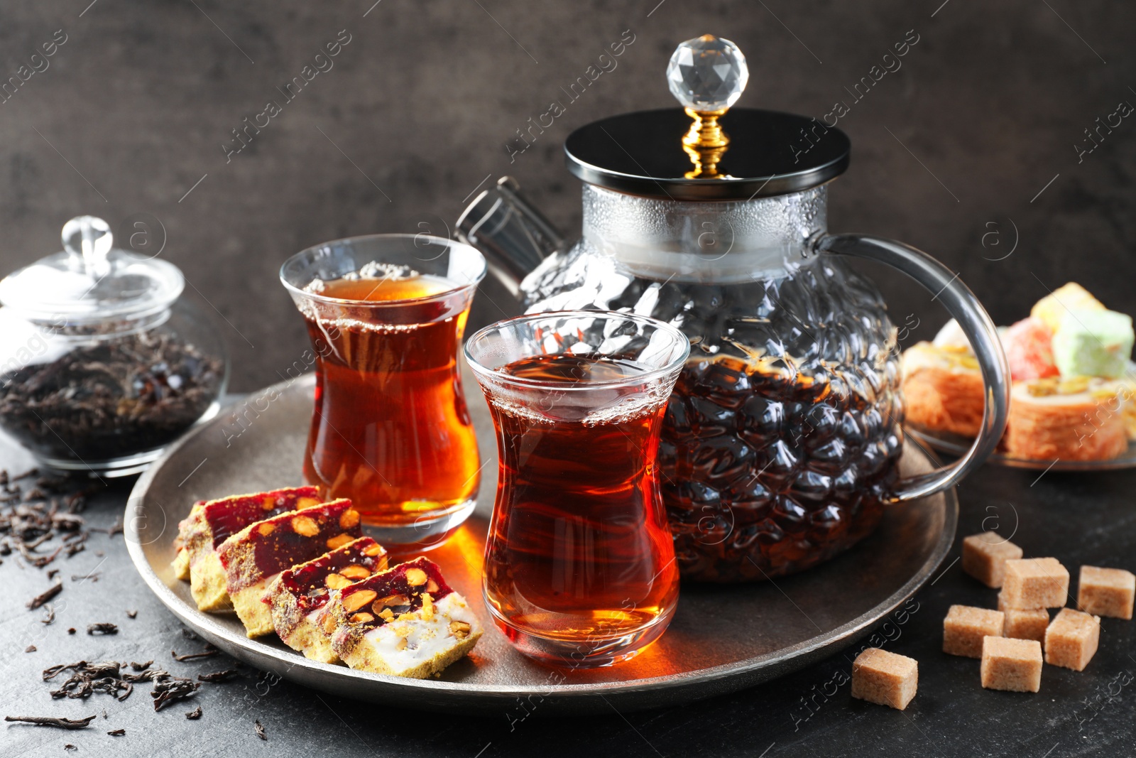 Tasty Turkish tea and delight on black table Photo of Tasty Turkish tea and delight on black table